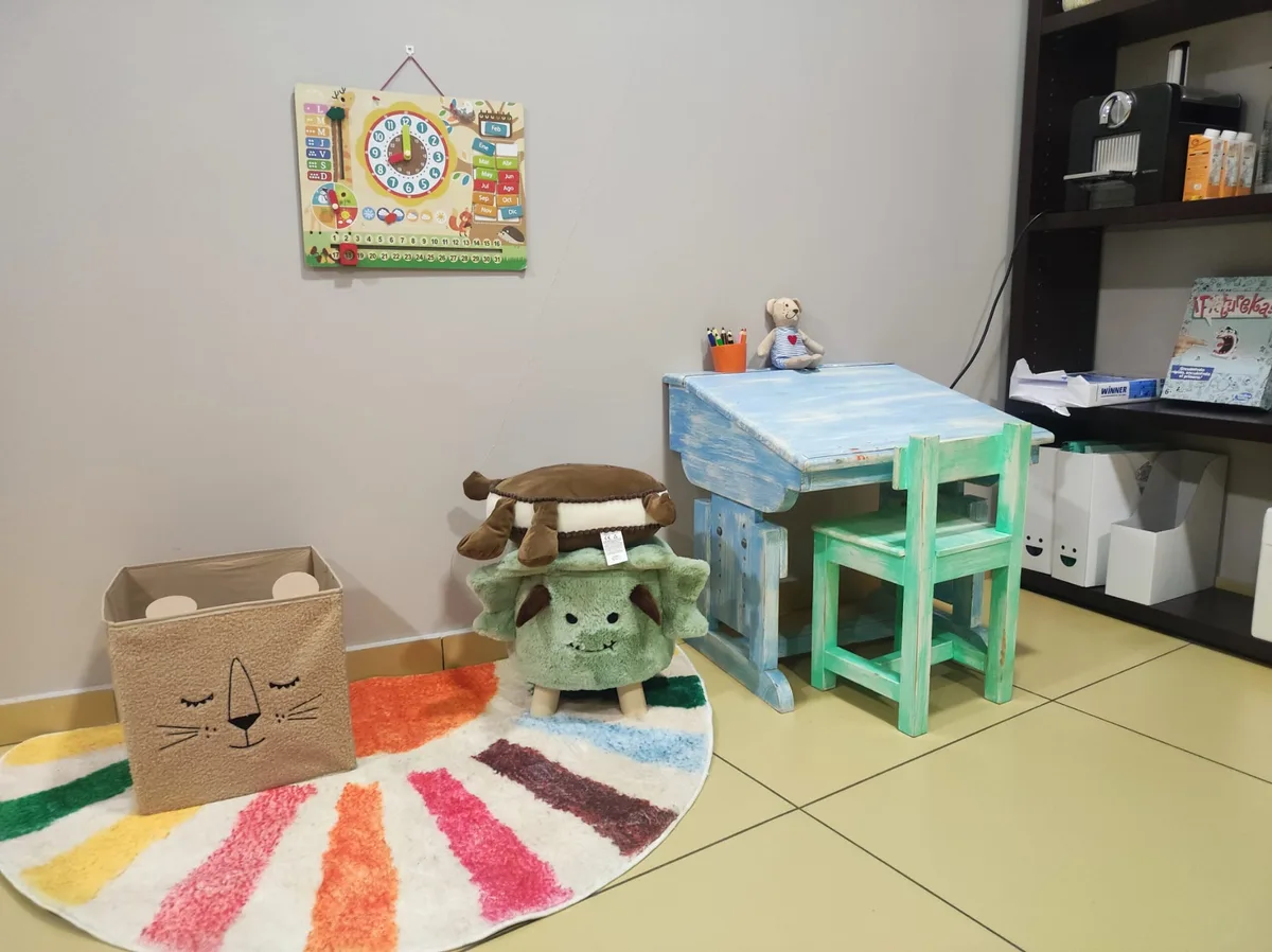 Zona infanto-juvenil con alfombra, mesa de actividades y peluches